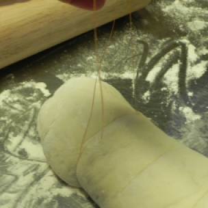 Wiggle the string under the dough and use it to cut into equal portions